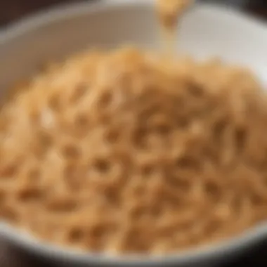 A close-up of creamy peanut sauce being drizzled over freshly cooked noodles